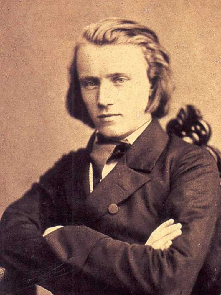 Composer Johannes Brahms seated with arms folded, 1853 Wikimedia Commons image Hans Zwickau